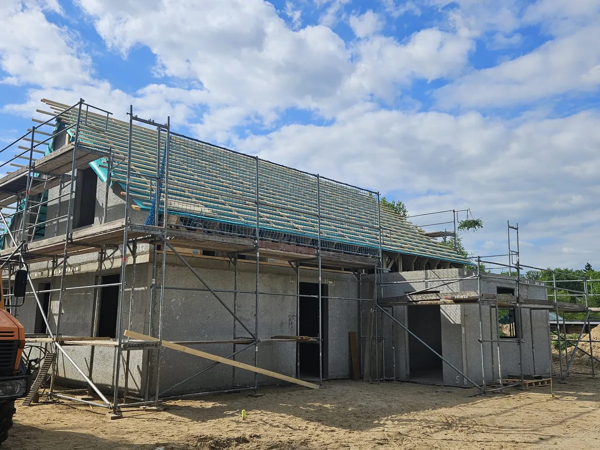 Scaffolded house with insulated roof truss under a blue sky