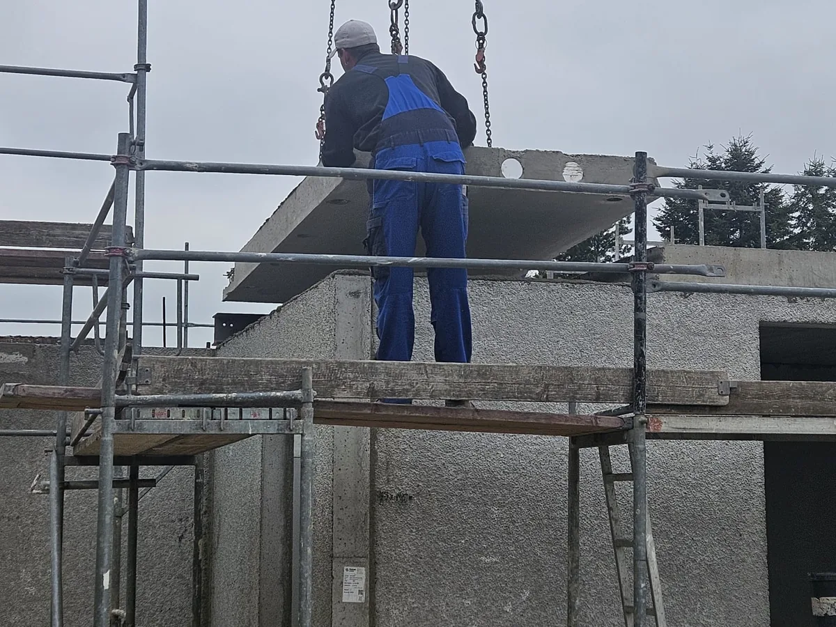 A fitter aligns a wall element from the scaffolding